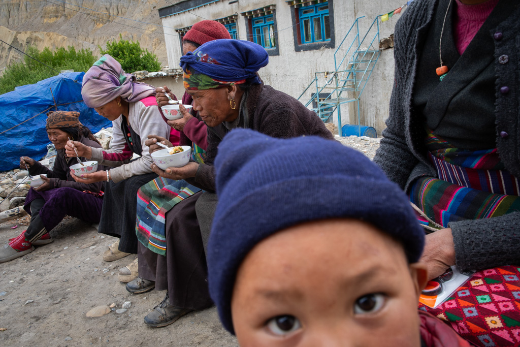 a young Nepalese man in the foreground and other people in the background wearing colorful clothes
