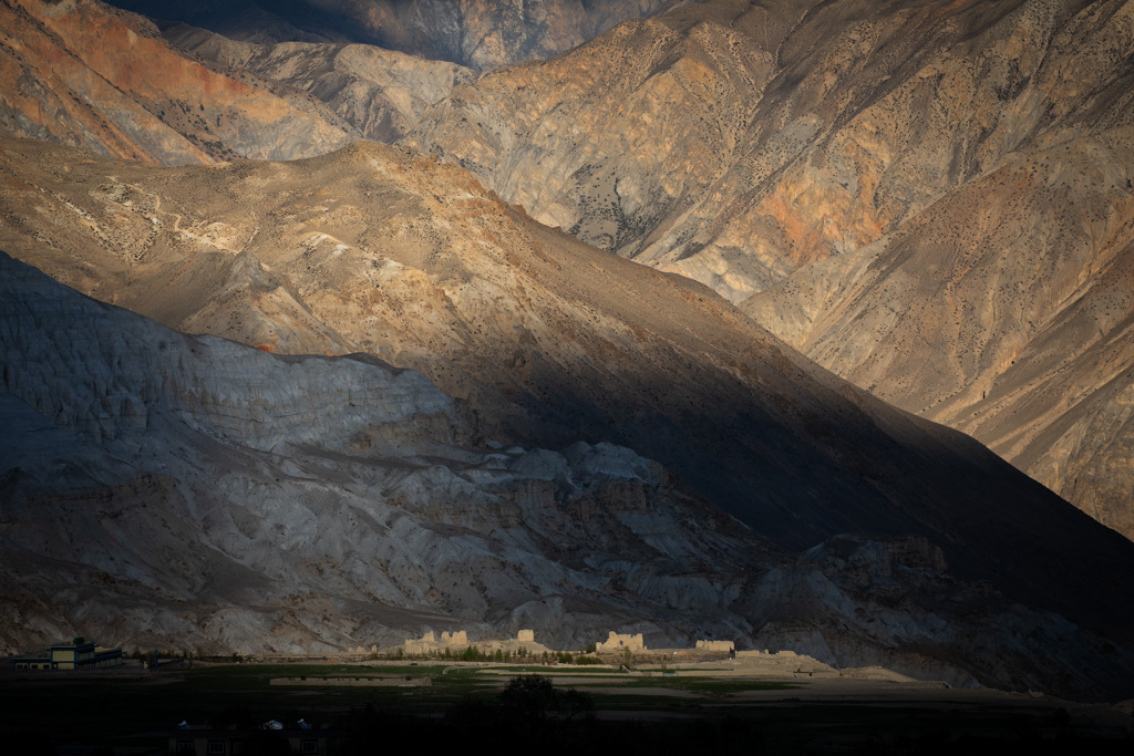 a small village in the background overlooked by mountains and in the shade